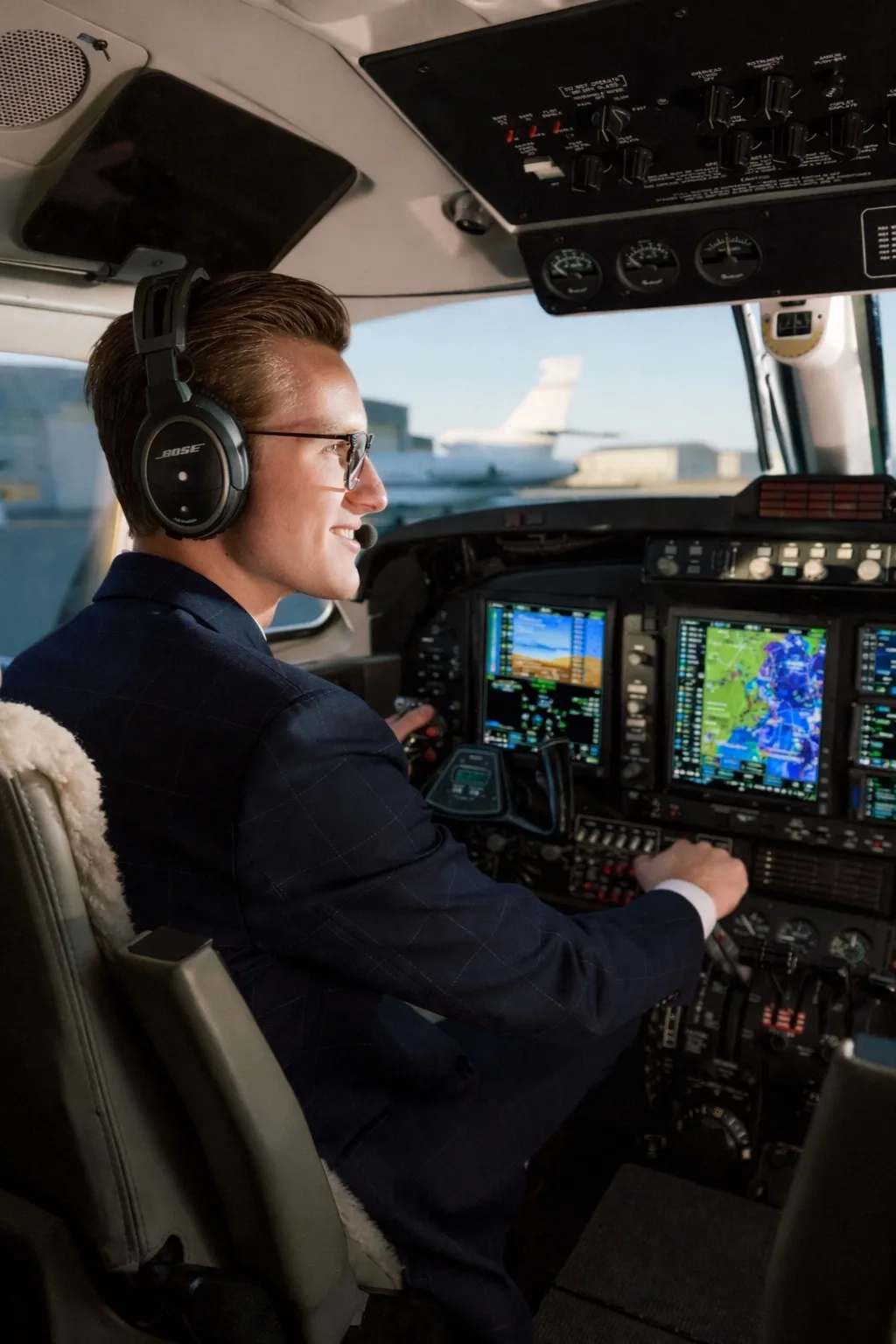 A pilot at the controls of a business aircraft flight deck
